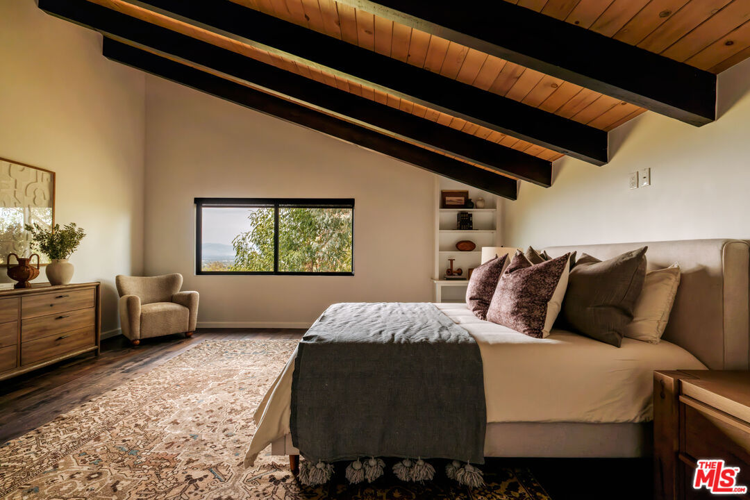 Bedroom beneath a sloped wood-beamed ceiling