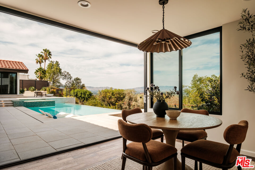 Round breakfast table beside floor-to-ceiling windows overlooking the pool