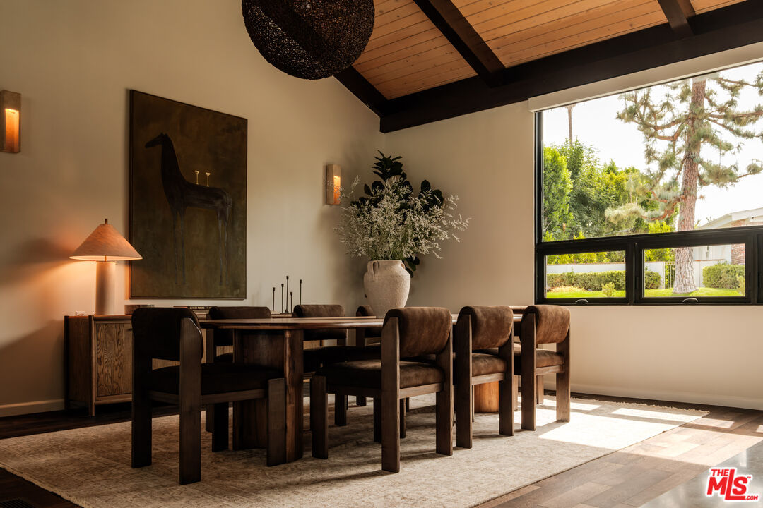 Evening dining room with carved wood table beneath a woven pendant light