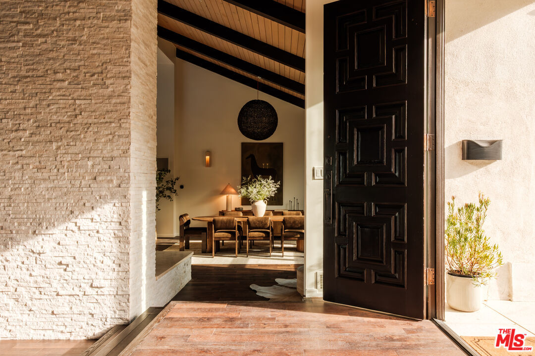 Hand-carved dark wood front door opening to the dining room and vaulted ceiling beyond