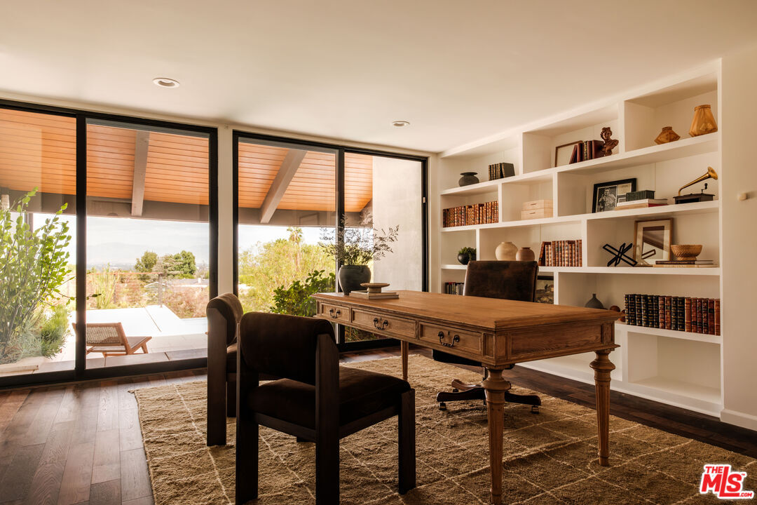 Home office with a writing desk, built-in library shelving, and sliding glass doors to the terrace
