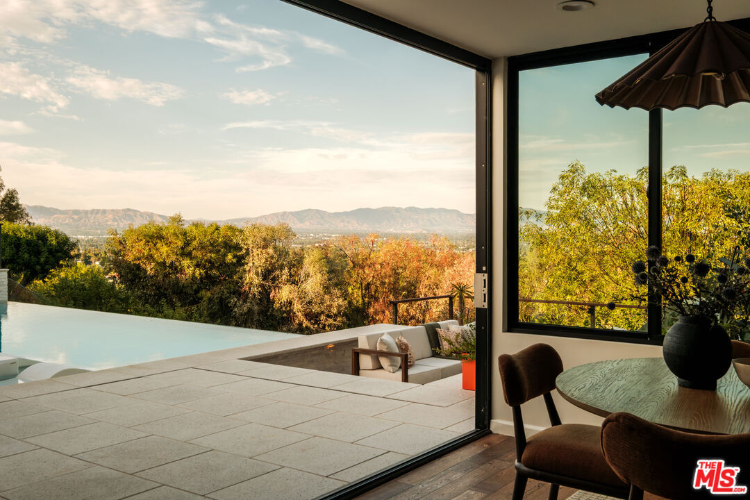 Sliding glass doors open from the dining nook directly onto the infinity pool deck and sunken fire-pit lounge