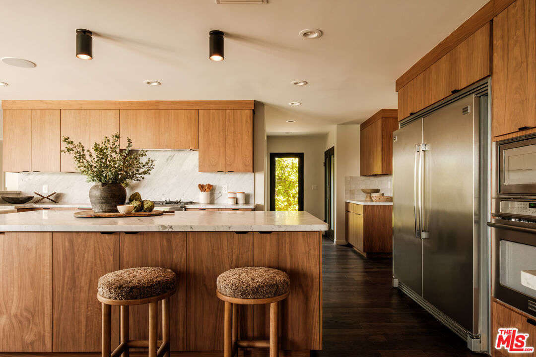 Walnut kitchen with waterfall marble island and integrated paneled appliances