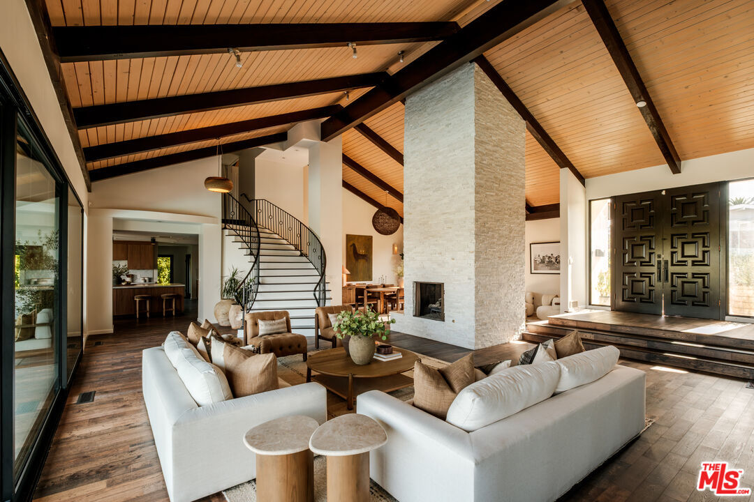 Grand living room with spiral staircase and full-height stacked-stone fireplace