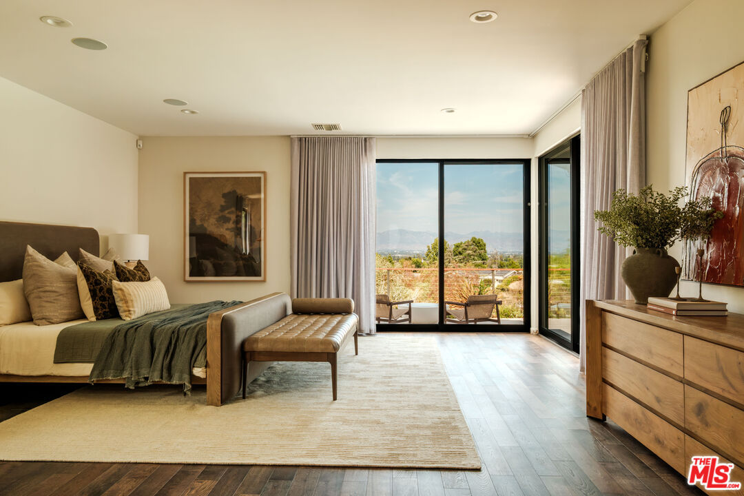Primary bedroom with corner sliding doors opening directly onto the spa and pool deck